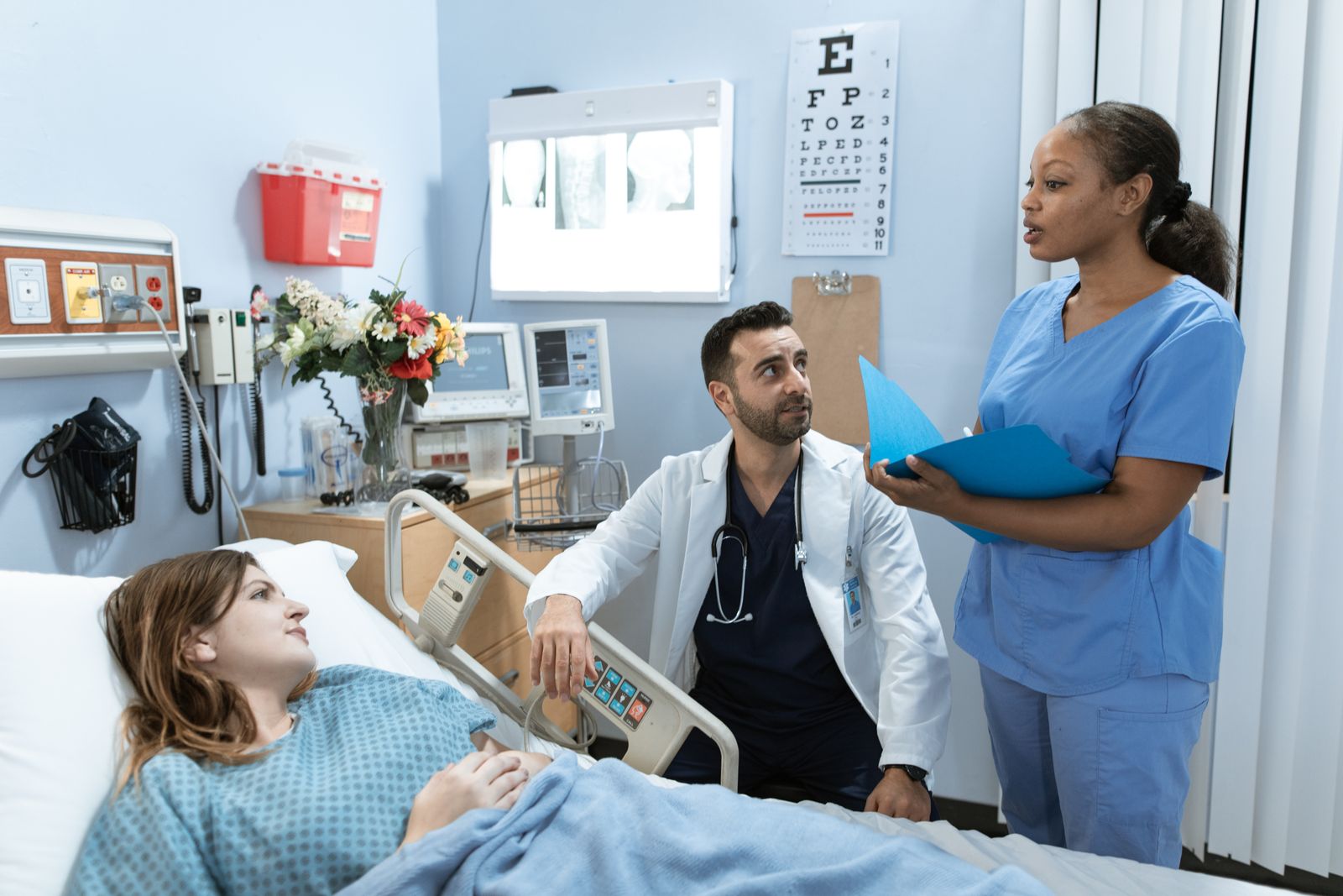 Black nurse and doctor speaking with a patient in a hospital room