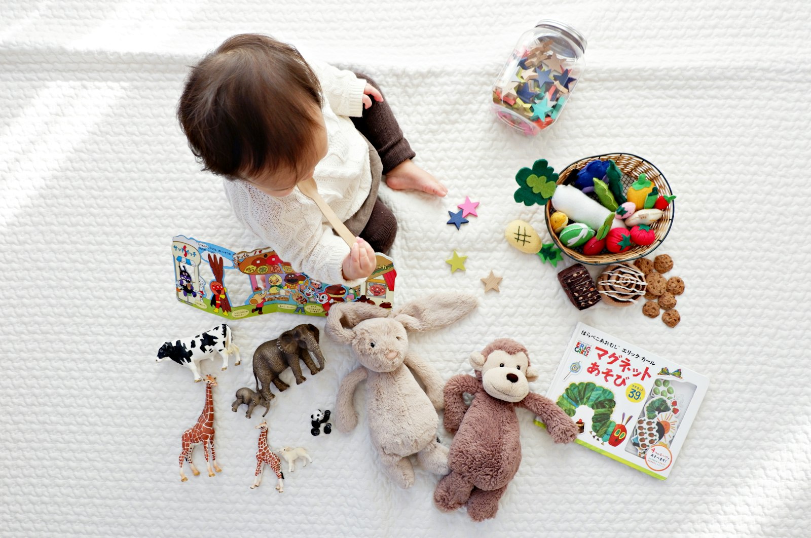 East Asian toddler playing with toys on a blanket